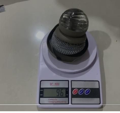 Modern automatic soap dispenser placed on a digital scale showing 96.7 grams weight