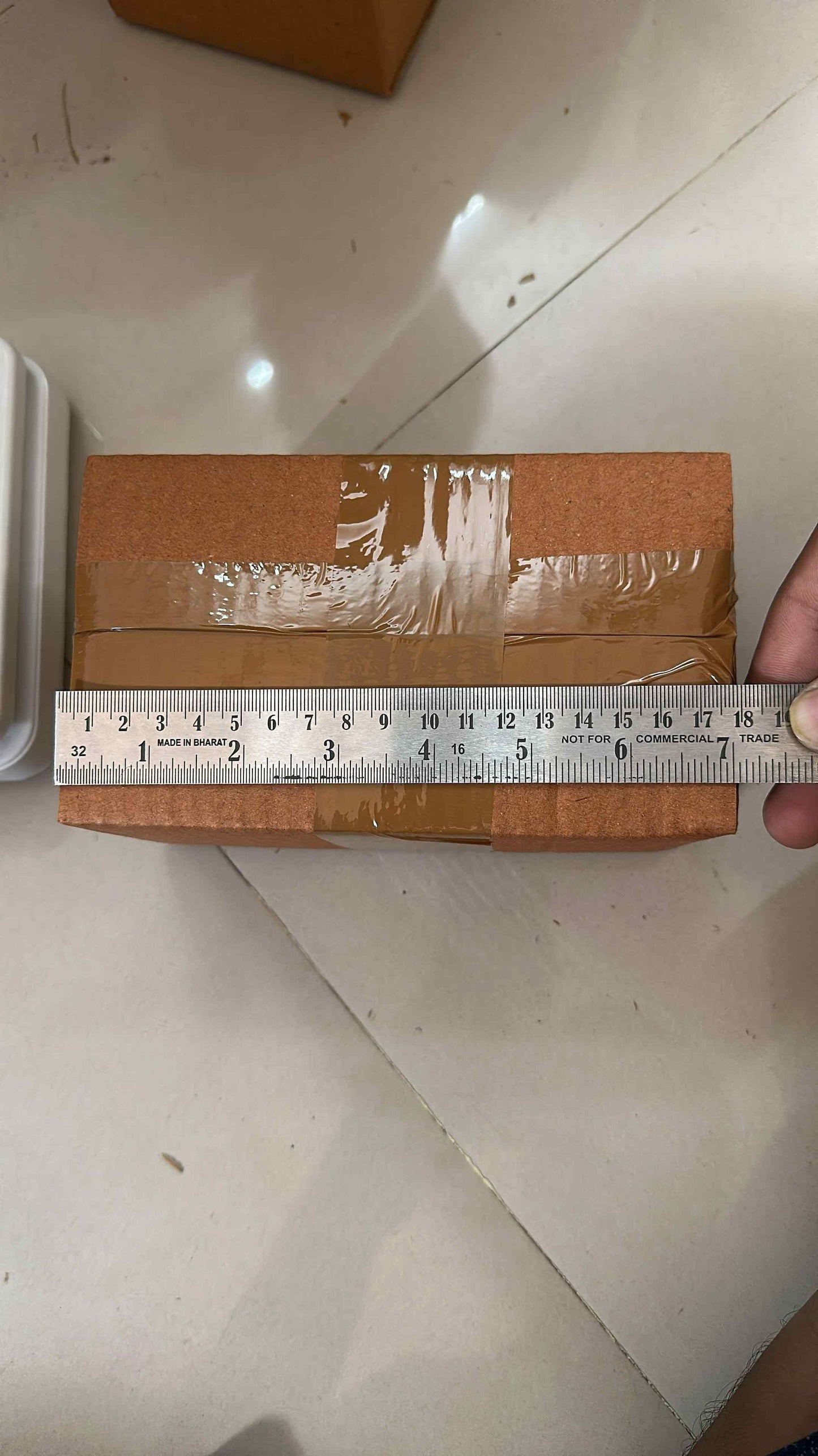 Measuring fireproof adhesive tape for kitchen on a sealed brown cardboard box with a metal ruler