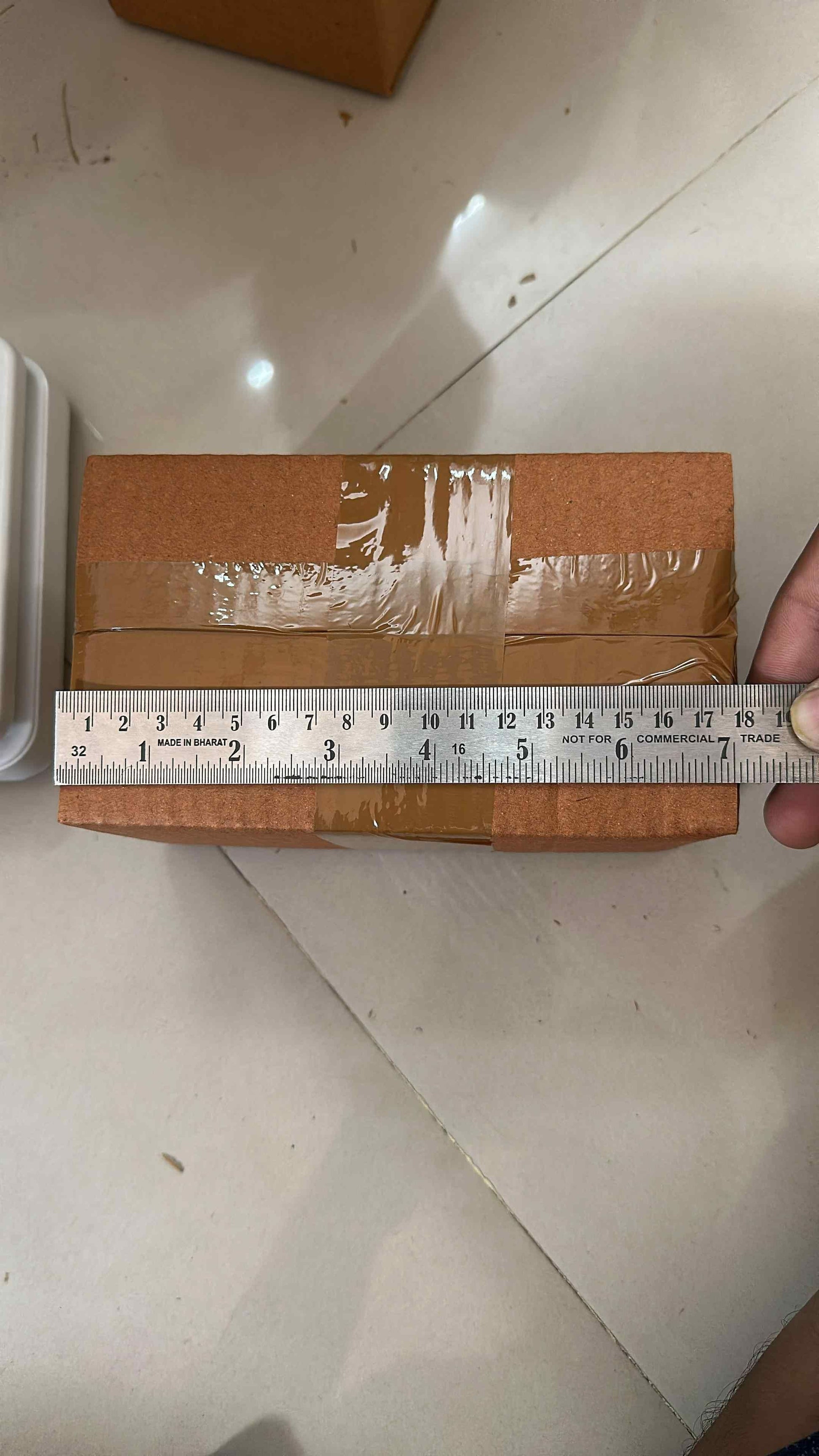 Measuring fireproof adhesive tape for kitchen on a sealed brown cardboard box with a metal ruler