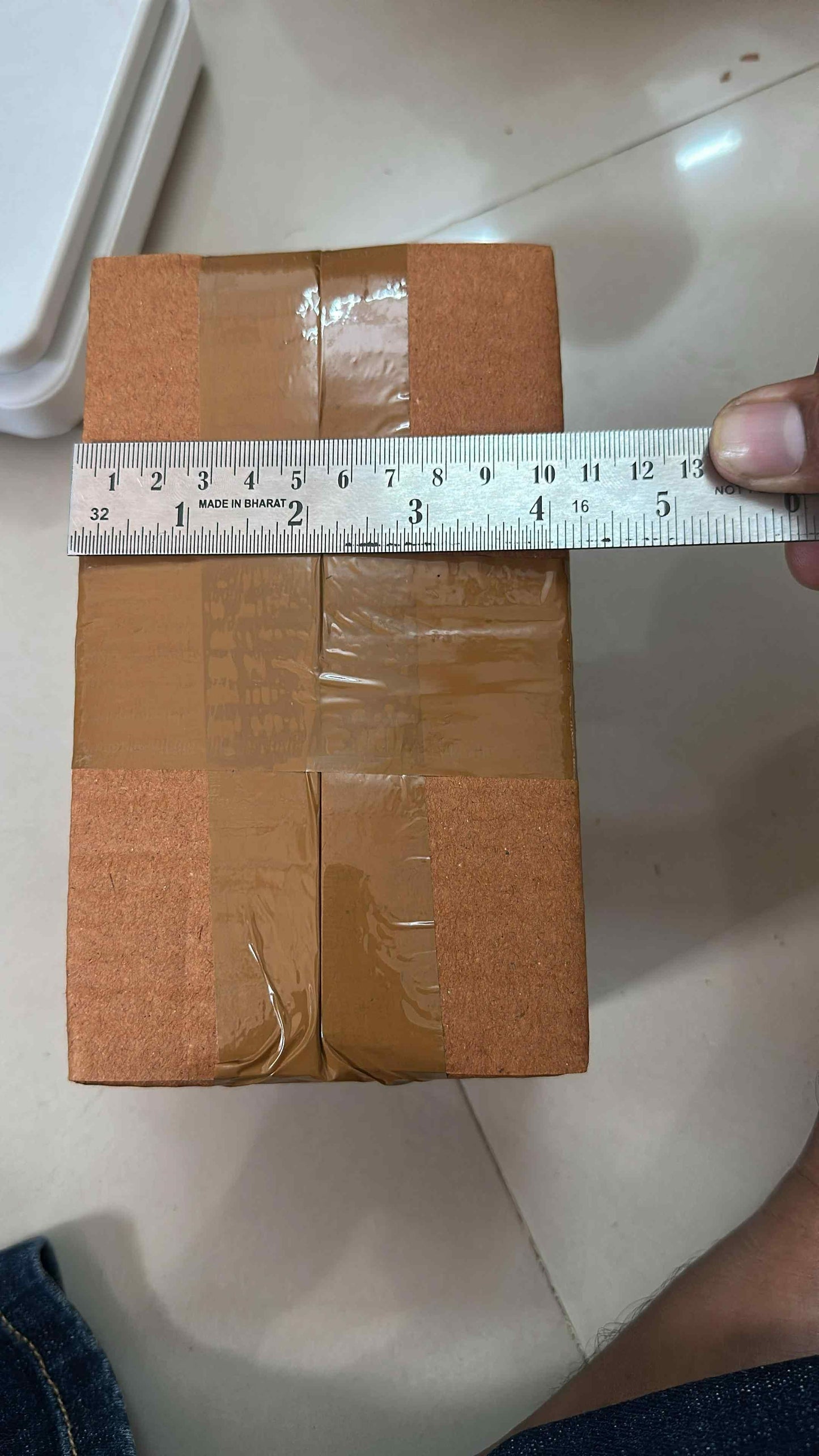 Measuring a sealed cardboard box with a metal ruler for fireproof adhesive tape for kitchen