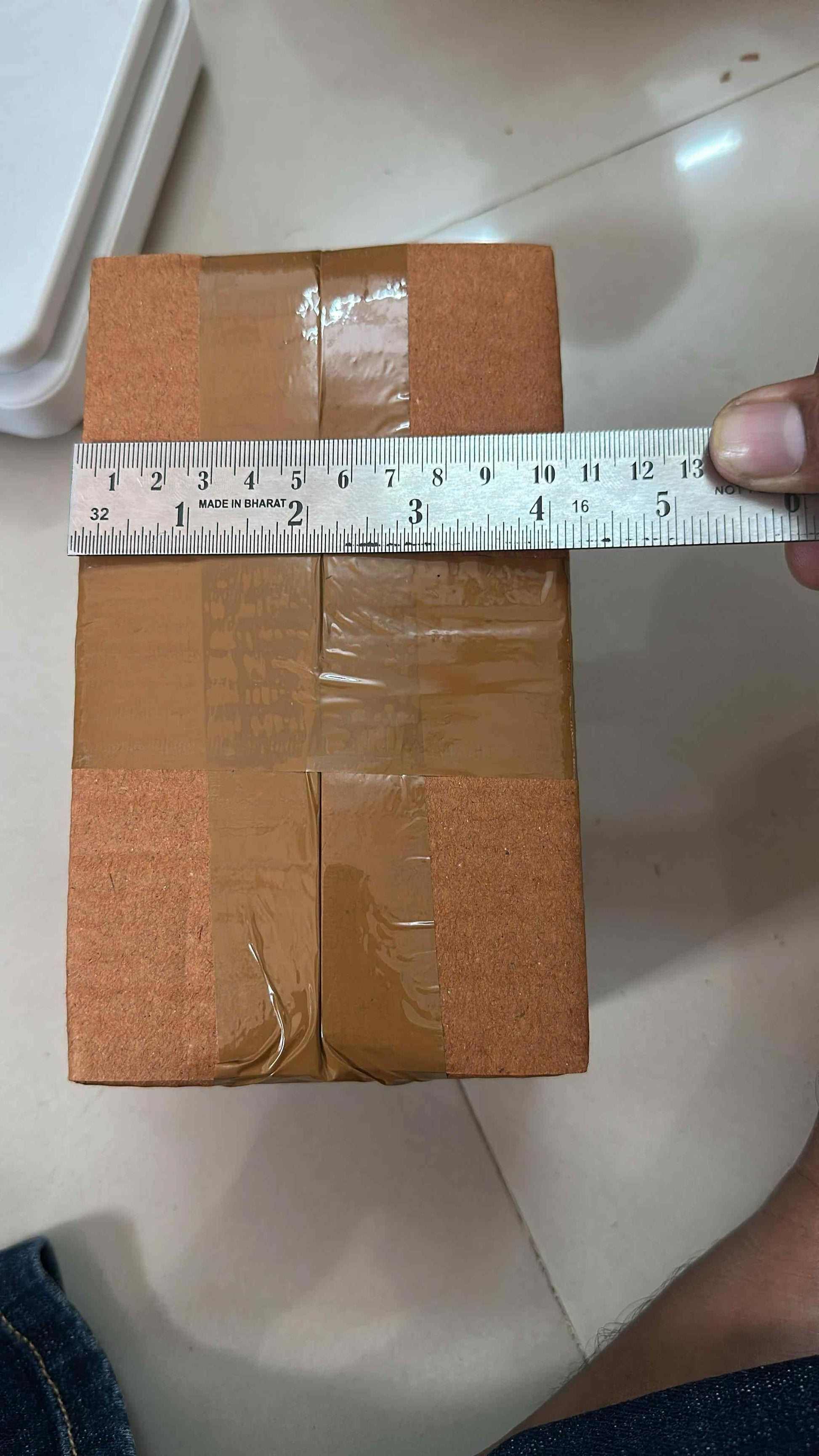 Measuring a sealed cardboard box with a metal ruler for fireproof adhesive tape for kitchen