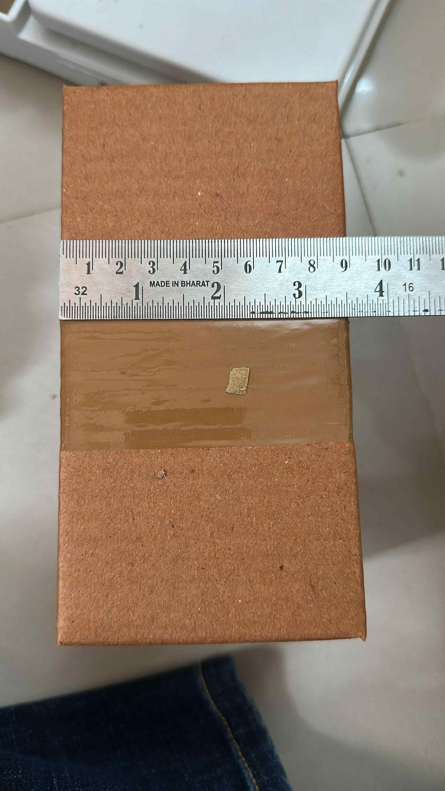 Fireproof adhesive tape for kitchen packaged in a brown cardboard box with a ruler for size reference