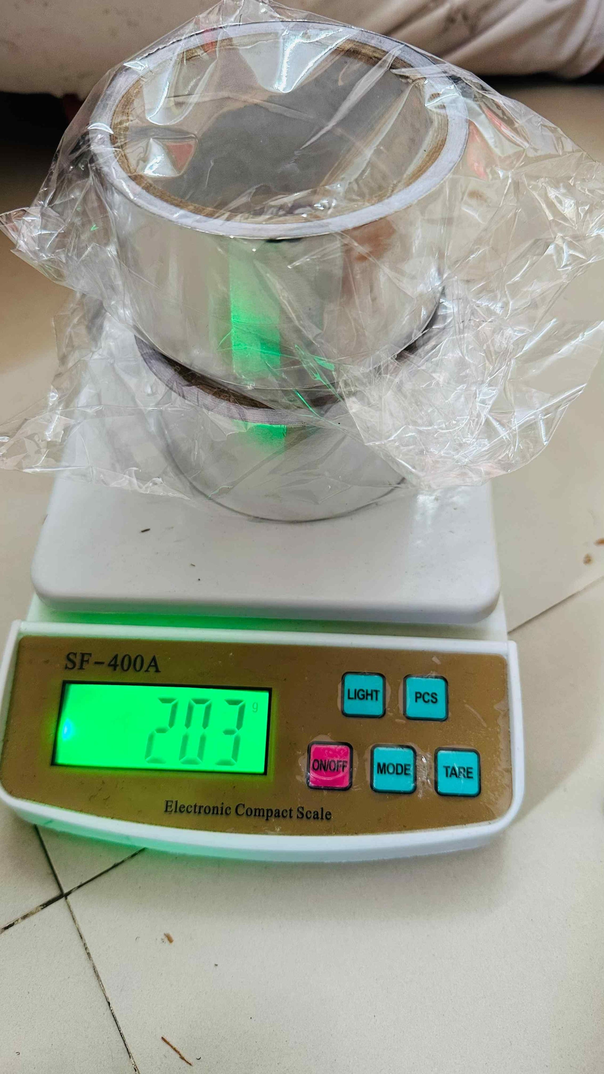 Roll of fireproof adhesive tape for kitchen placed on an electronic compact scale showing weight