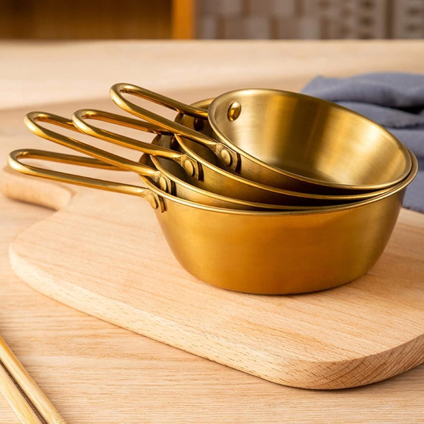 Stack of gold kitchen bowl with handle for ramen on wooden cutting board in kitchen setting